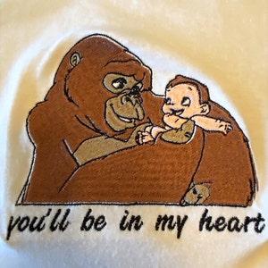 Puede incluir: Dise&ntilde;o bordado de un gorila marr&oacute;n sosteniendo un peque&ntilde;o beb&eacute; marr&oacute;n claro sonriente. El texto "you'll be in my heart" est&aacute; bordado debajo de la imagen.