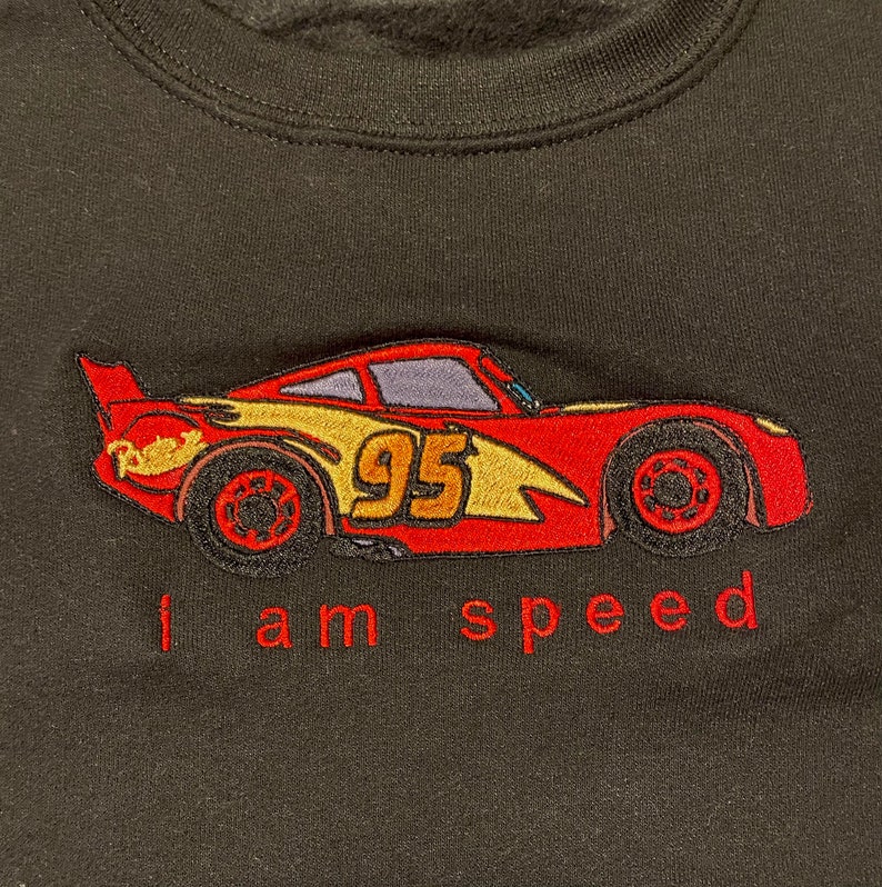 May include: Black sweatshirt with a red embroidered image of a race car with the number 95 on the side. The text "I am speed" is embroidered below the car.