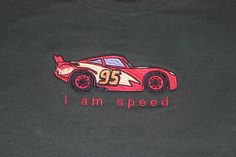 May include: Red and black embroidered design of a race car with the number 95 on the side. The text "i am speed" is below the car.
