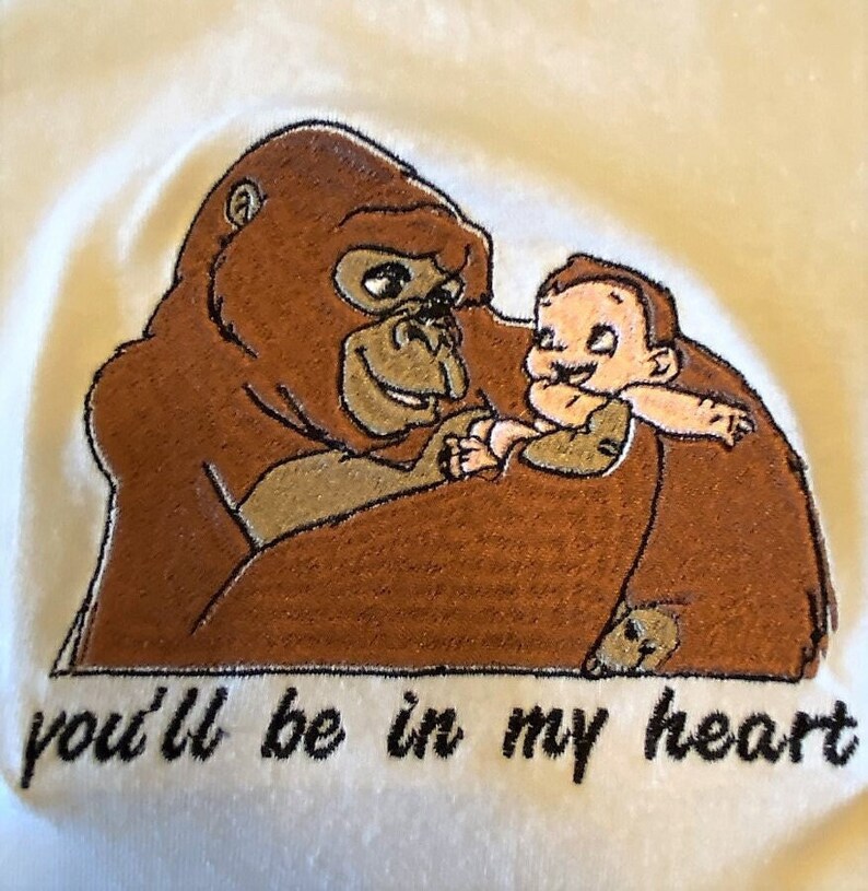 Puede incluir: Dise&ntilde;o bordado de un gorila marr&oacute;n sosteniendo un peque&ntilde;o beb&eacute; marr&oacute;n claro sonriente. El texto "you'll be in my heart" est&aacute; bordado debajo de la imagen.
