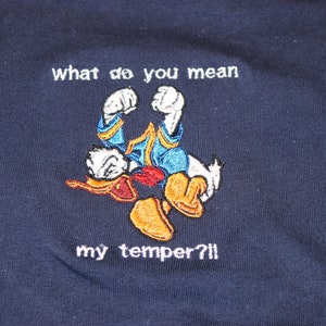 May include: A navy blue t-shirt with an embroidered image of Donald Duck with the text "what do you mean my temper?!"