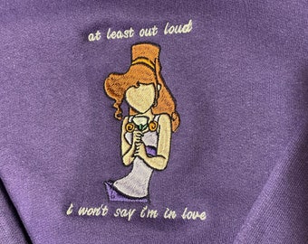 May include: Purple sweatshirt with embroidered image of a woman holding a flower and the text "at least out loud I won't say I'm in love".