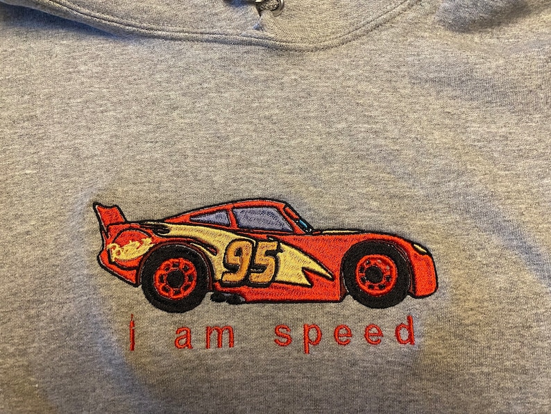 May include: Gray hooded sweatshirt with an embroidered image of a red race car with the number 95 on the side. The text "I am speed" is embroidered below the car.