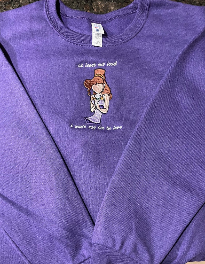May include: Purple sweatshirt with an embroidered image of a woman with a crown and the text "at least out loud I won't say I'm in love"