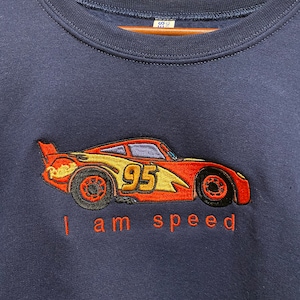May include: A navy blue sweatshirt with an embroidered image of a red race car with the number 95 on the side. The text "I am speed" is embroidered below the car.