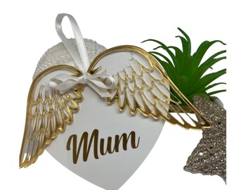 May include: White heart-shaped ornament with gold angel wings and the word "Mum" written in gold lettering.