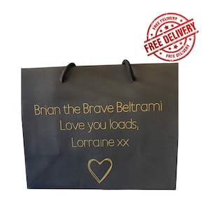 May include: A black gift bag with a gold heart and the text "Brian the Brave Beltrami Love you loads, Lorraine xx" printed on the front.