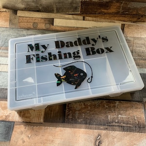 May include: A white plastic tackle box with a black and iridescent fish graphic and the text "My Daddy's Fishing Box".