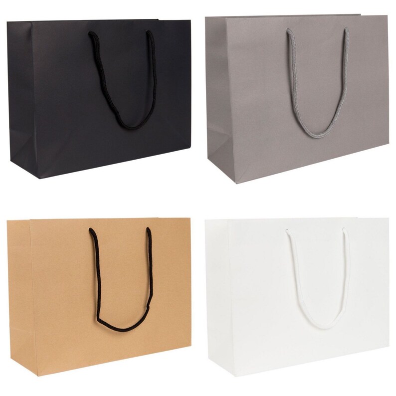 May include: Four paper gift bags in different colours: black, grey, brown, and white. Each bag has a pair of rope handles.