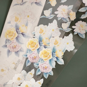 May include: A sheet of clear stickers featuring watercolour illustrations of white and yellow flowers. The flowers are arranged in a bouquet with green leaves. The stickers are ideal for adding a touch of elegance to journals, planners, and other paper crafts.