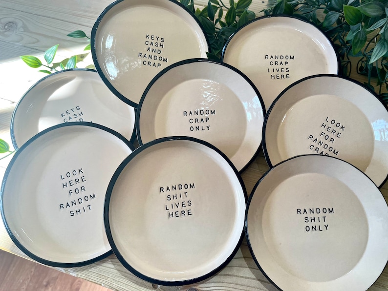 Może przedstawiać: Siedem białych ceramicznych talerzy z czarnymi obw&oacute;dkami, każdy z innym humorystycznym powiedzeniem. Powiedzenia obejmują: "Klucze Got&oacute;wka i Losowy Bałagan", "Losowy Bałagan Mieszka Tutaj", "Tylko Losowy Bałagan", "Sp&oacute;jrz Tutaj Po Losowy Bałagan", "Sp&oacute;jrz Tutaj Po Losowy G&oacute;wniany Bałagan", "Losowy G&oacute;wniany Bałagan Mieszka Tutaj", i "Tylko Losowy G&oacute;wniany Bałagan".