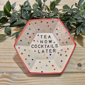 Puede incluir: Un plato hexagonal de cer&aacute;mica con un borde rojo y un fondo blanco. El plato est&aacute; decorado con lunares de colores y el texto "TEA NOW COCKTAILS LATER".
