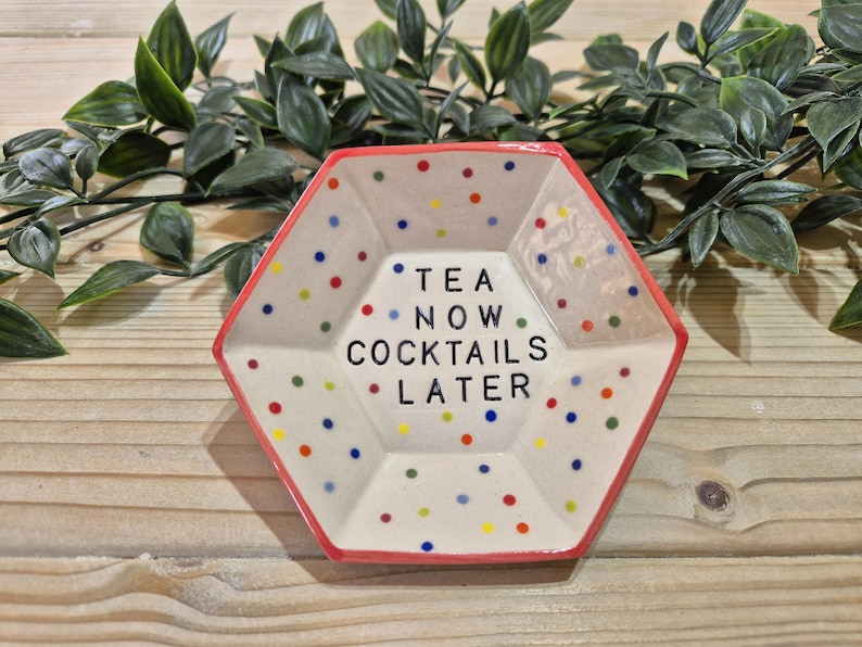 Puede incluir: Un plato hexagonal de cer&aacute;mica con un borde rojo y un fondo blanco. El plato est&aacute; decorado con lunares de colores y el texto "TEA NOW COCKTAILS LATER".