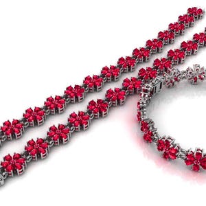May include: Three pieces of jewellery: two bracelets and one bracelet-style necklace. Each piece features a floral design with bright red gemstones set in a silver-coloured metal. The bracelets have clasps.
