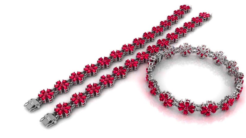 May include: Three pieces of jewellery: two bracelets and one bracelet-style necklace. Each piece features a floral design with bright red gemstones set in a silver-coloured metal. The bracelets have clasps.