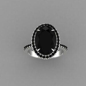 May include: A silver ring featuring a large, oval-cut black gemstone surrounded by a halo of smaller black stones. Additional black stones are set along the band, creating a striking contrast against the silver.
