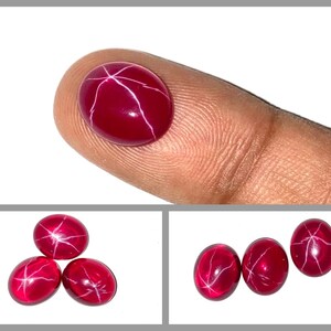Puede incluir: Tres cabujones de rubí estrella roja con patrones de estrellas blancas. Los cabujones son de forma ovalada y tienen una superficie lisa y pulida.