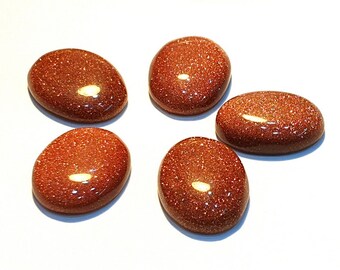 May include: Five oval-shaped, polished, red-brown sunstone cabochons. The stones have a sparkly, glittery appearance.