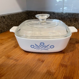 May include: White casserole dish with a blue floral design and a clear glass lid.