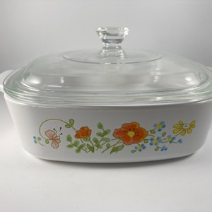 Pu&ograve; includere: Piatto da forno bianco con coperchio in vetro e un motivo floreale con fiori arancioni, rosa, gialli e blu.