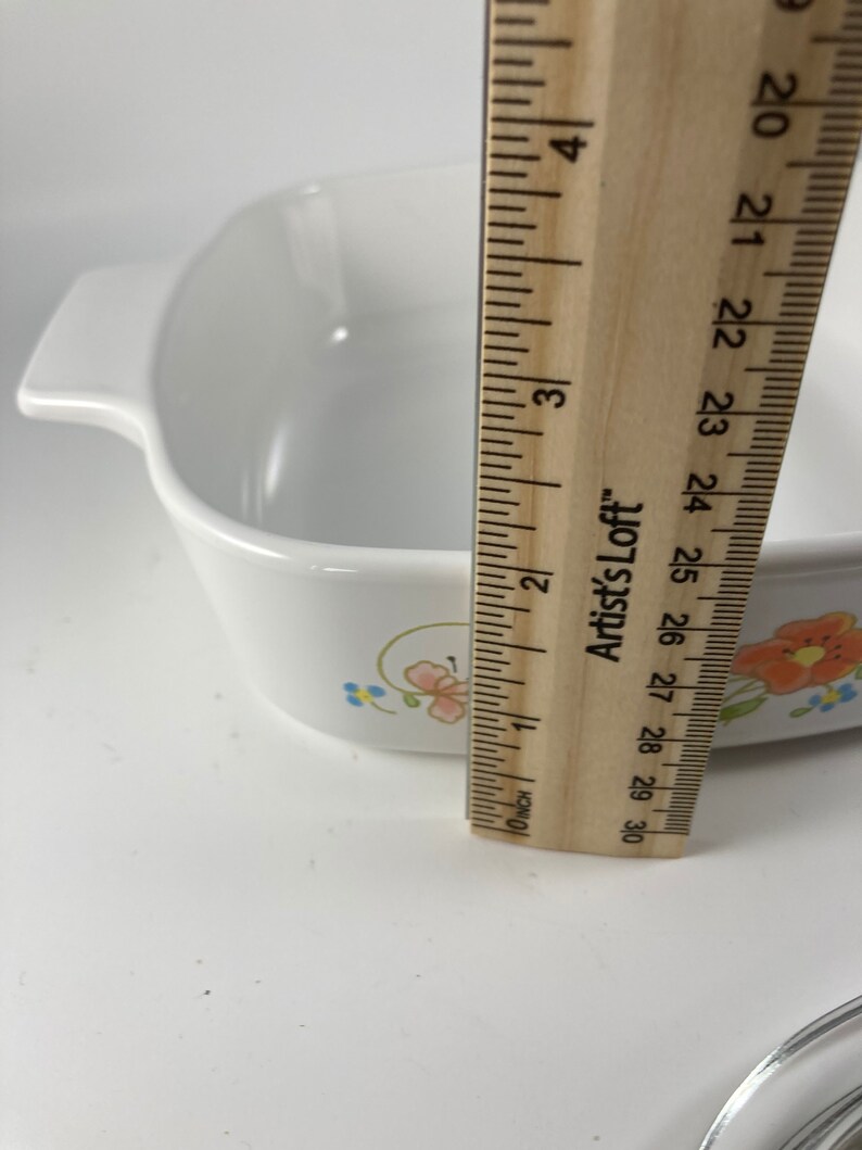 Pu&ograve; includere: Piatto da forno in ceramica bianca con un motivo floreale in tonalit&agrave; rosa, blu e giallo. Il piatto &egrave; largo 18 cm e ha un manico su ogni lato.