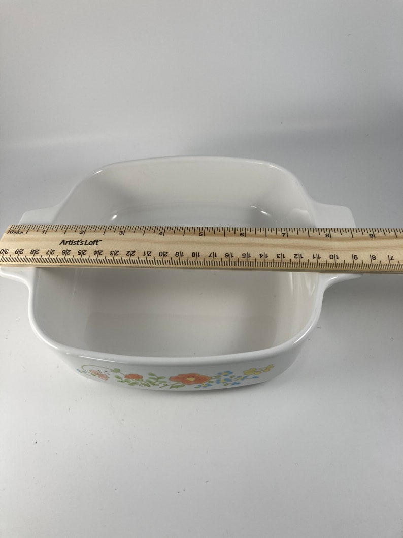 Pu&ograve; includere: Piatto da forno in ceramica bianca con un design floreale con fiori arancioni, gialli, blu e verdi. Il piatto &egrave; largo circa 23 cm.