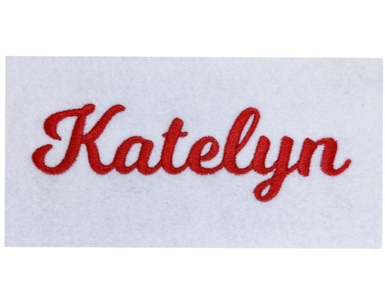 May include: Red embroidered name "Katelyn" on a white fabric background.