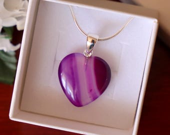 May include: A silver chain necklace with a purple and white heart-shaped agate pendant. The pendant is in a white gift box.