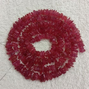 Puede incluir: Una hebra de cuentas de rubí rosa. Las cuentas son de forma irregular y tienen un acabado rugoso y natural.