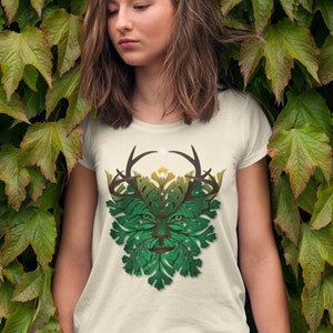 May include: A white t-shirt with a green and brown leafy design of a face with antlers. The design is reminiscent of the Green Man, a mythical figure associated with nature.