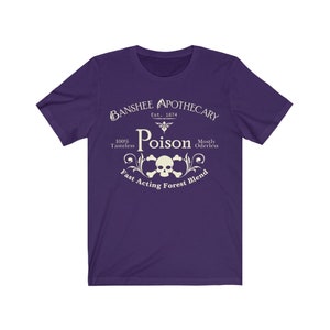 Puede incluir: Camiseta morada con un dise&ntilde;o gr&aacute;fico blanco que dice "Banshee Apothecary Est. 1874 Poison 100% Tasteless Mostly Oderless Fast Acting Forest Blend". El gr&aacute;fico tambi&eacute;n incluye una calavera y huesos cruzados.
