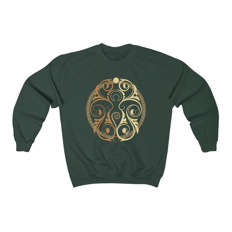 May include: A dark green sweatshirt with a gold and cream circular design featuring intricate swirls and patterns.