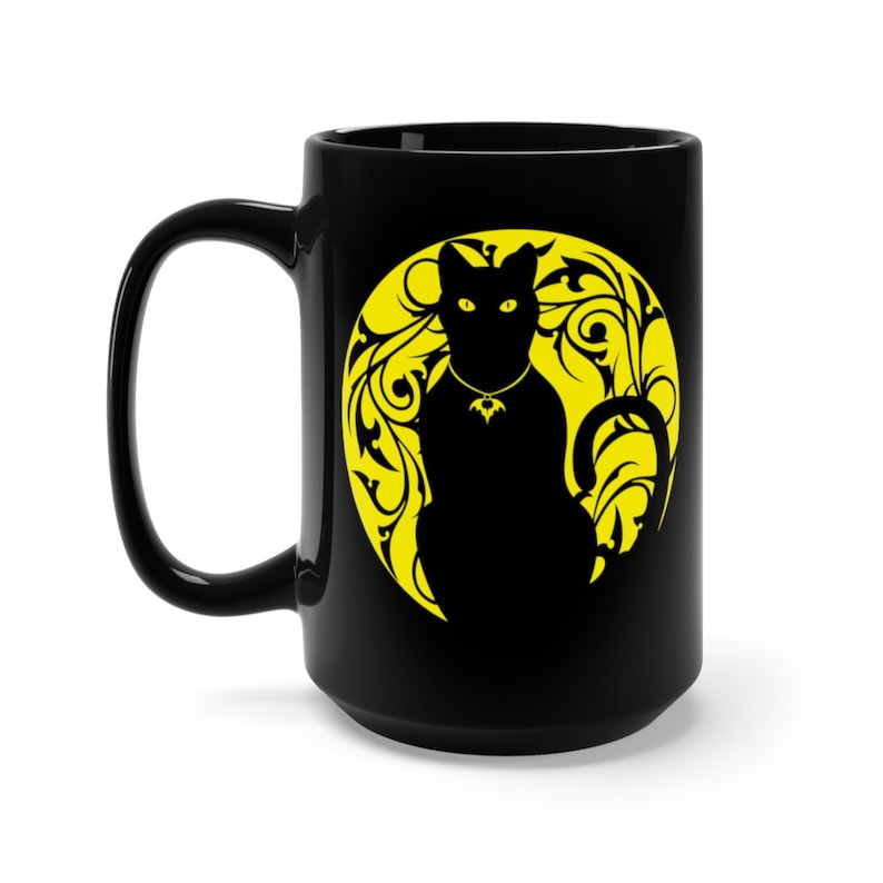 May include: Black coffee mug featuring a yellow silhouette of a cat sitting in a moon with floral designs.