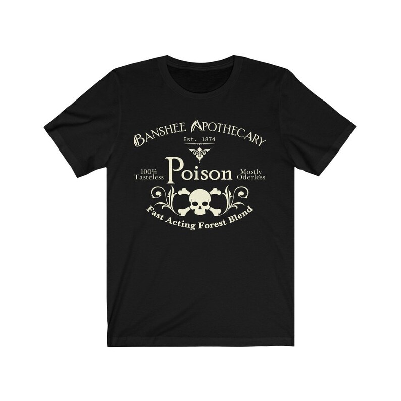 Puede incluir: Camiseta negra con un dise&ntilde;o gr&aacute;fico blanco que dice "Banshee Apothecary Est. 1874 Poison 100% Tasteless Mostly Oderless Fast Acting Forest Blend". El gr&aacute;fico tambi&eacute;n incluye una calavera y huesos cruzados.