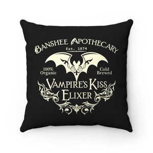 May include: Black throw pillow with a white design of a bat and the text "Banshee Apothecary Est. 1874 100% Organic Cold Brewed Vampire's Kiss Elixir"