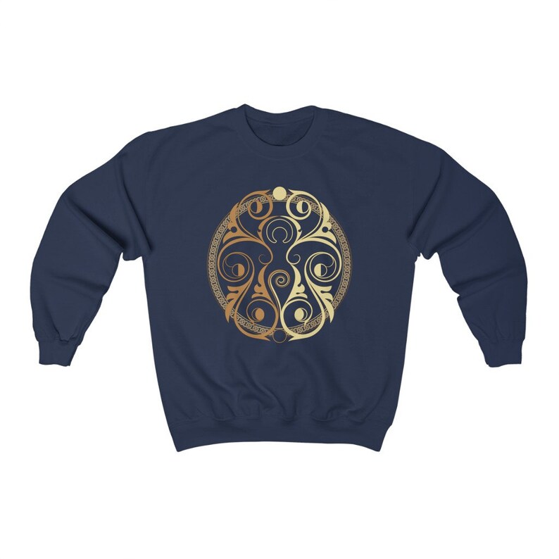 May include: A navy blue sweatshirt with a gold and cream colored circular design featuring a stylized floral pattern.