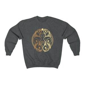 May include: A dark grey sweatshirt with a gold and cream circular design featuring intricate floral patterns.