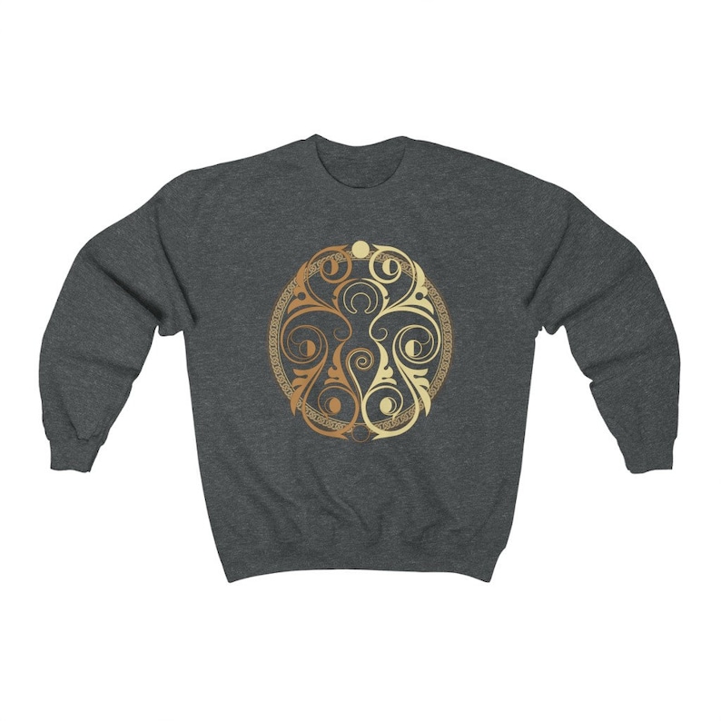 May include: A dark grey sweatshirt with a gold and cream circular design featuring intricate floral patterns.