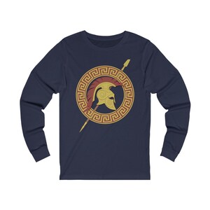 Pu&ograve; includere: Maglietta a maniche lunghe blu navy con un design a chiave greca dorata e un'immagine di un elmo spartano rosso e oro.