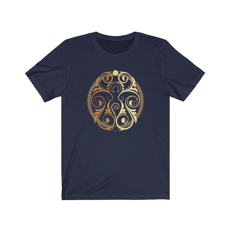 May include: A navy blue t-shirt with a gold circular design featuring intricate swirls and patterns.