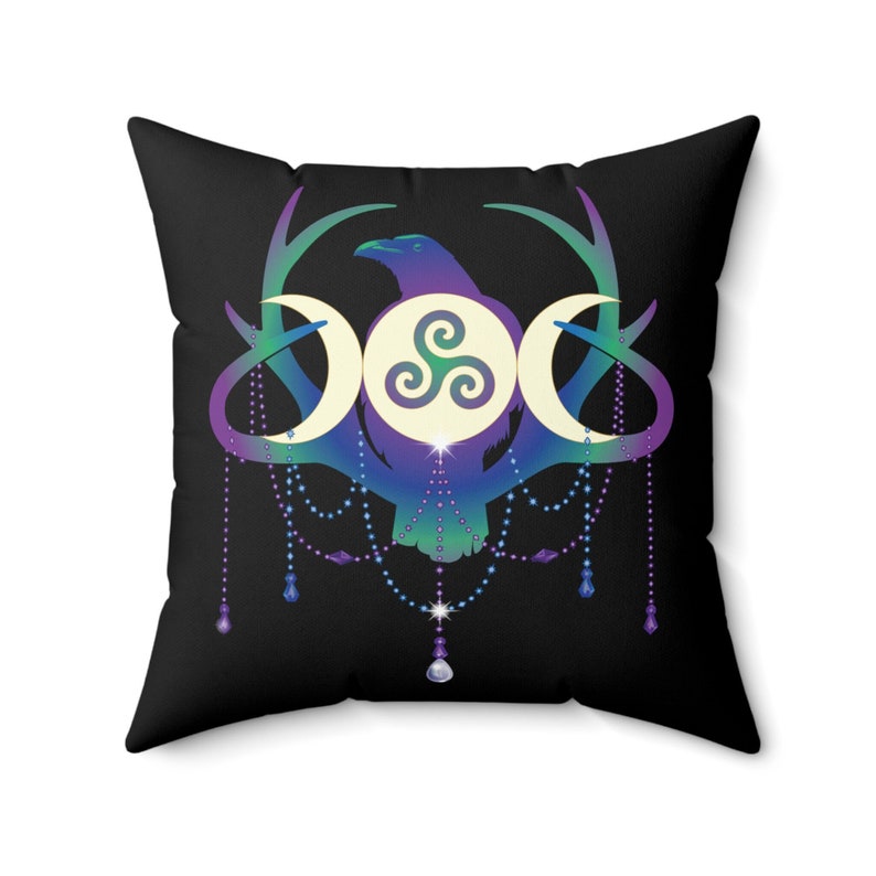 May include: A black throw pillow with a colourful design featuring a raven, three moons, and a triple spiral symbol. The design is surrounded by a beaded garland with crystal accents.