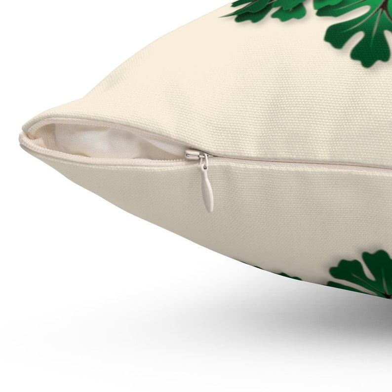 May include: A white pillow with a zipper closure. The pillow has a green leafy design on the front.