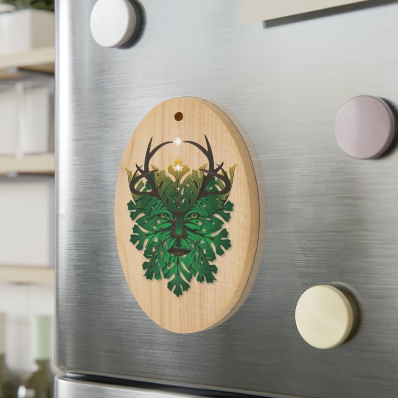 Peut inclure: Une d&eacute;coration ovale en bois avec un motif vert et marron d'un Homme Vert avec des bois. L'Homme Vert est entour&eacute; de feuilles et de fleurs.