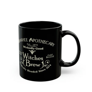 May include: Black ceramic mug with a white design that reads "Banshee Apothecary Est. 1874 Wickedly Good Witches Brew Magically Blended Since 1874 Cold Brewed".