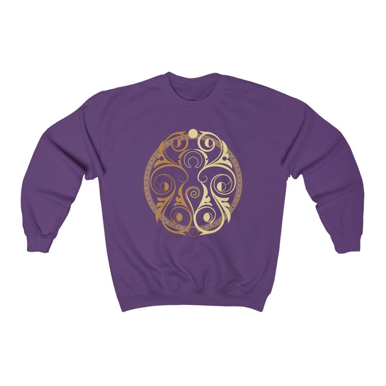 May include: Purple sweatshirt with a gold and cream colored circular design featuring a stylized floral pattern.