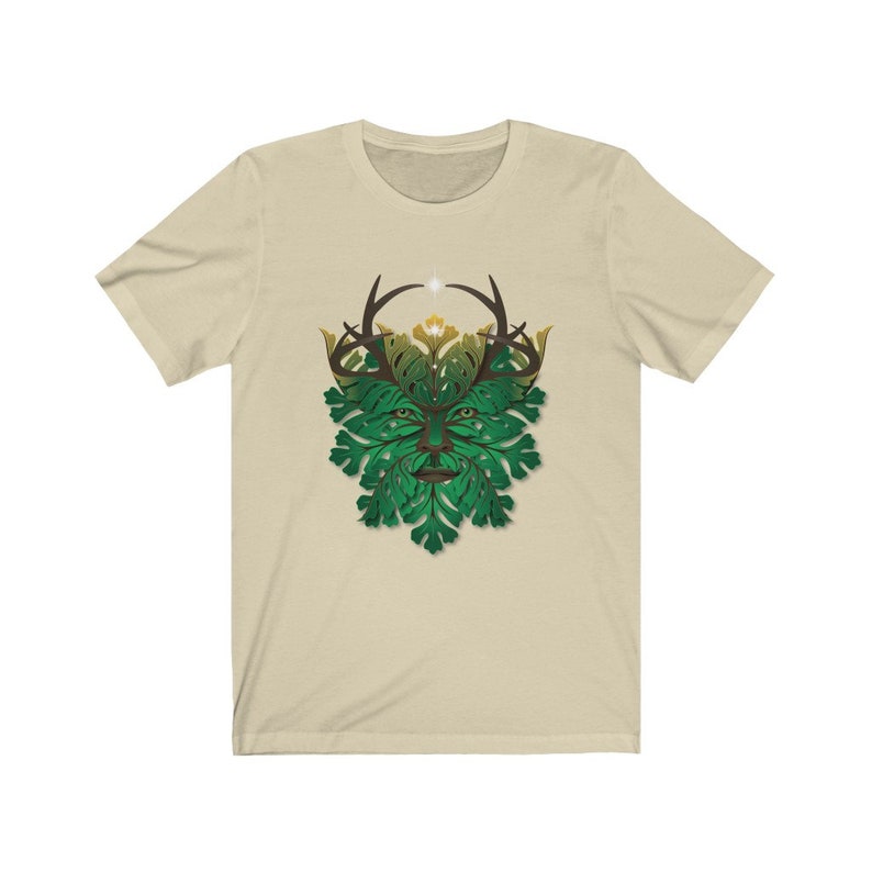 May include: A beige t-shirt with a green and brown graphic of a Green Man with antlers. The Green Man is a mythical figure representing nature and the cycle of life.