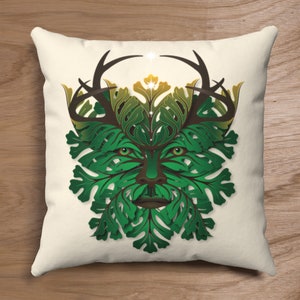 May include: A decorative cushion featuring a stylised green man face with antlers and leaves. The face is surrounded by a wreath of leaves and flowers.