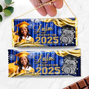 May include: Two graduation-themed candy bar wrappers with a gold chain. The wrappers feature a photo of a smiling person in a graduation cap and gown, the name "Lailas", "Graduation 2025", and a bulldog graphic. The background is blue and gold.