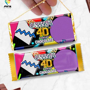 以下が含まれることがあります： 90 年代のテーマのチョコレートバーの包装が 2 つ。包装は黒、紫、黄、青で、金色のチェーンのデザインが施されています。包装のテキストは「GASSY'S 40th BIRTHDAY CHOCOLATE」です。
