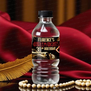 Op de afbeelding: Een doorzichtige plastic waterfles met een zwarte dop en een etiket met de tekst "Florence's Harlem Nights 30th Birthday". Het etiket toont een vintage auto-illustratie en een vrouwensilhouet. De fles staat tegen een rode stoffen achtergrond.